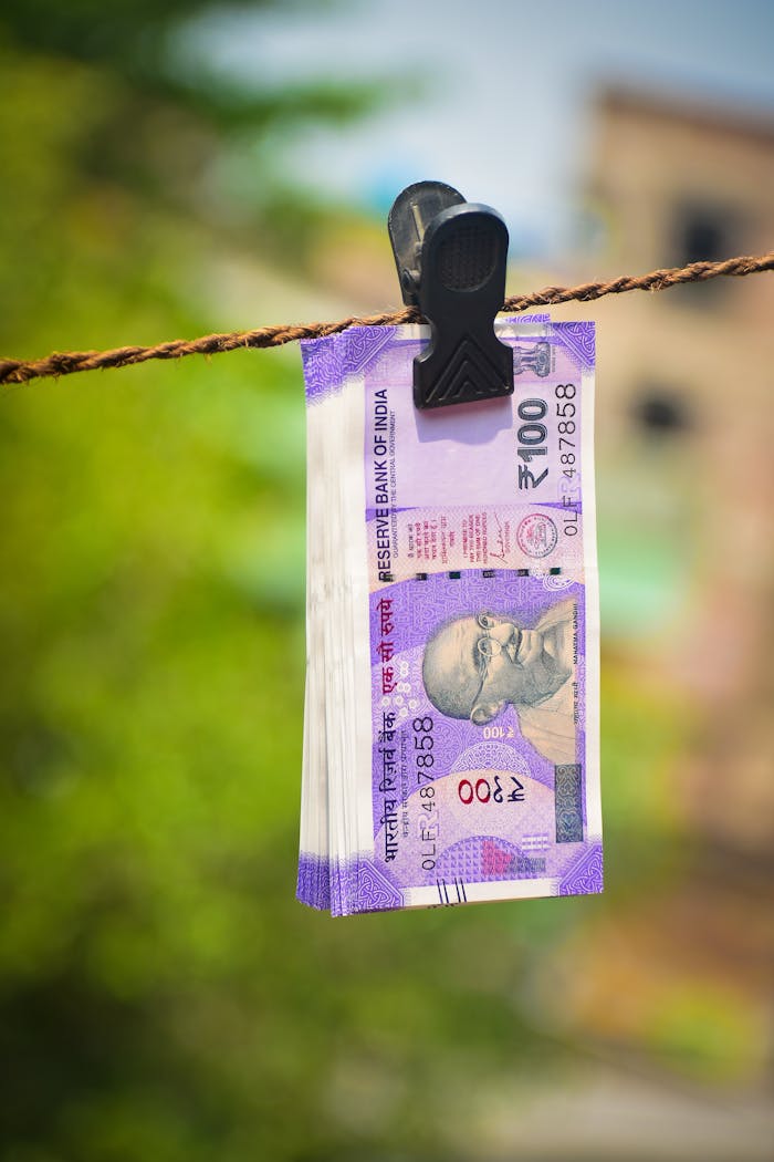 our-story Close-up of Indian 100 rupee notes clipped on a rope outdoors in Kolkata.